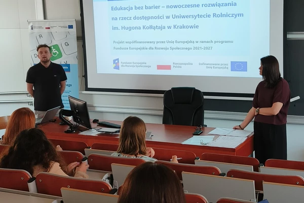 Zdjęcie przedstawia uczestników szkolenia 4 uczestników i 2 trenerów na auli. Na ekranie rzutnika widać  nazwę projektu i loga unijne. Po lewej stronie znajduje się rollup projektu.